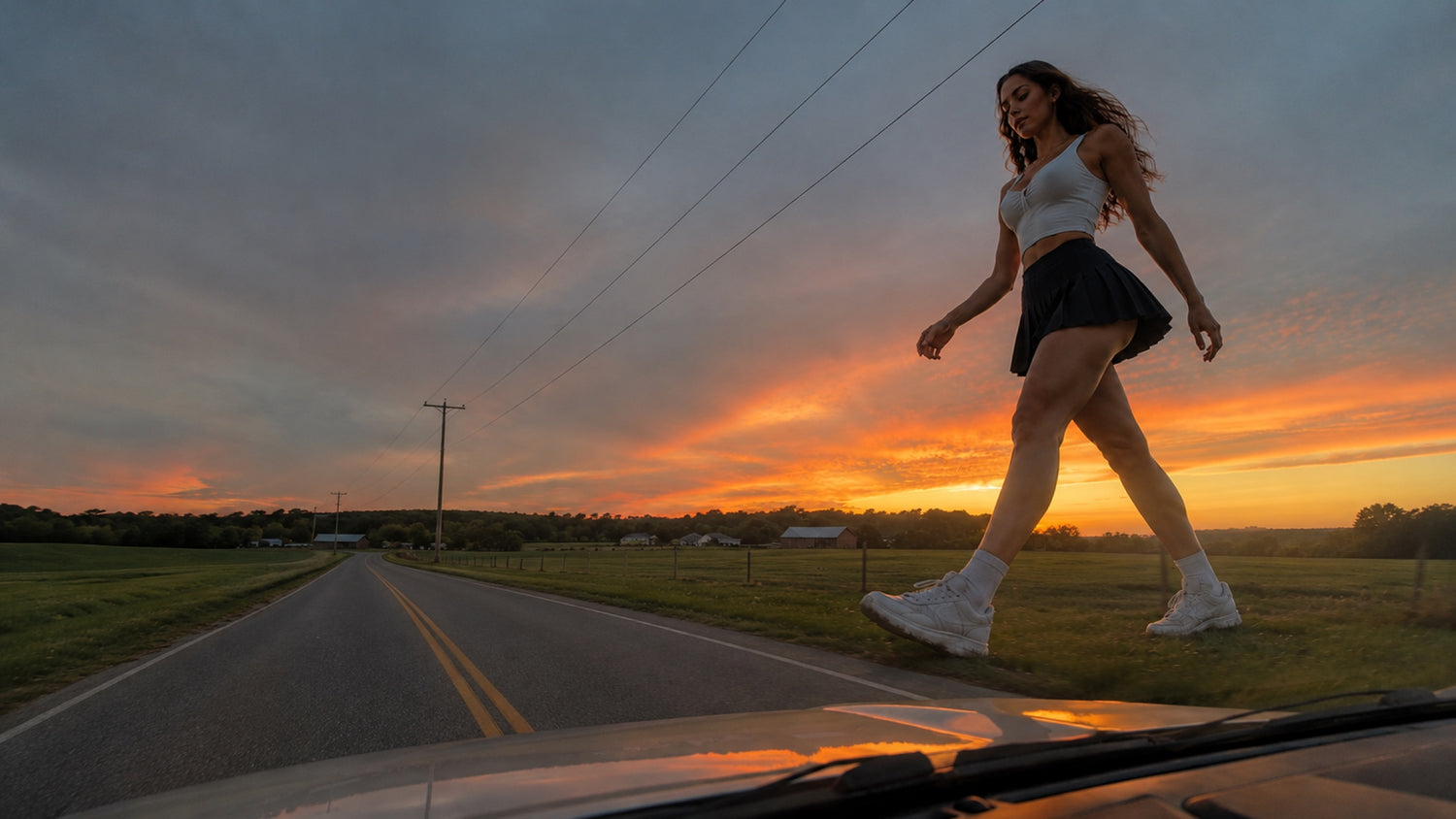 A giant woman strides across a rural two-lane road at sunset, seen from the hood of a following car.